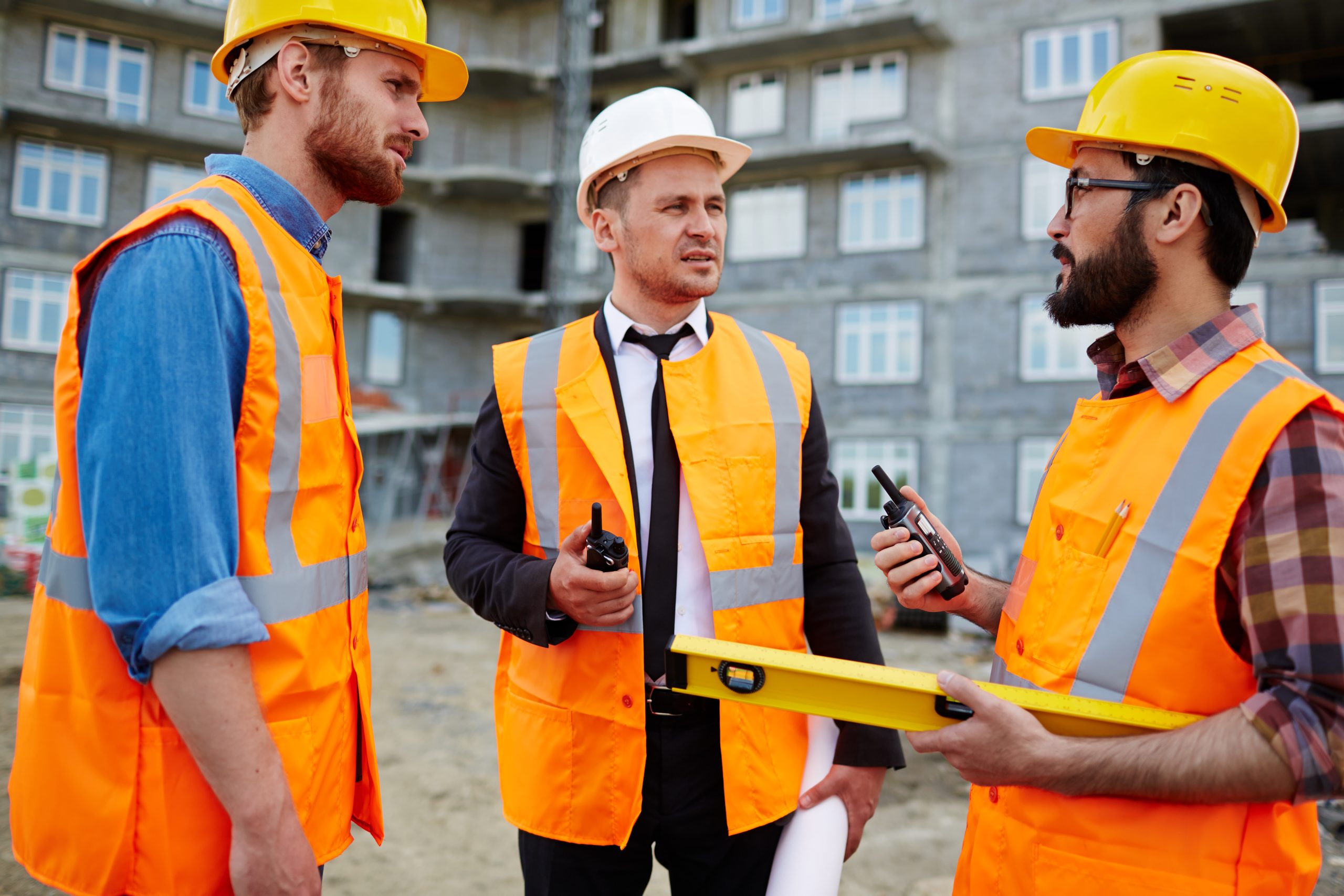 Subcontractors and a site manager with a tablet on a construction site