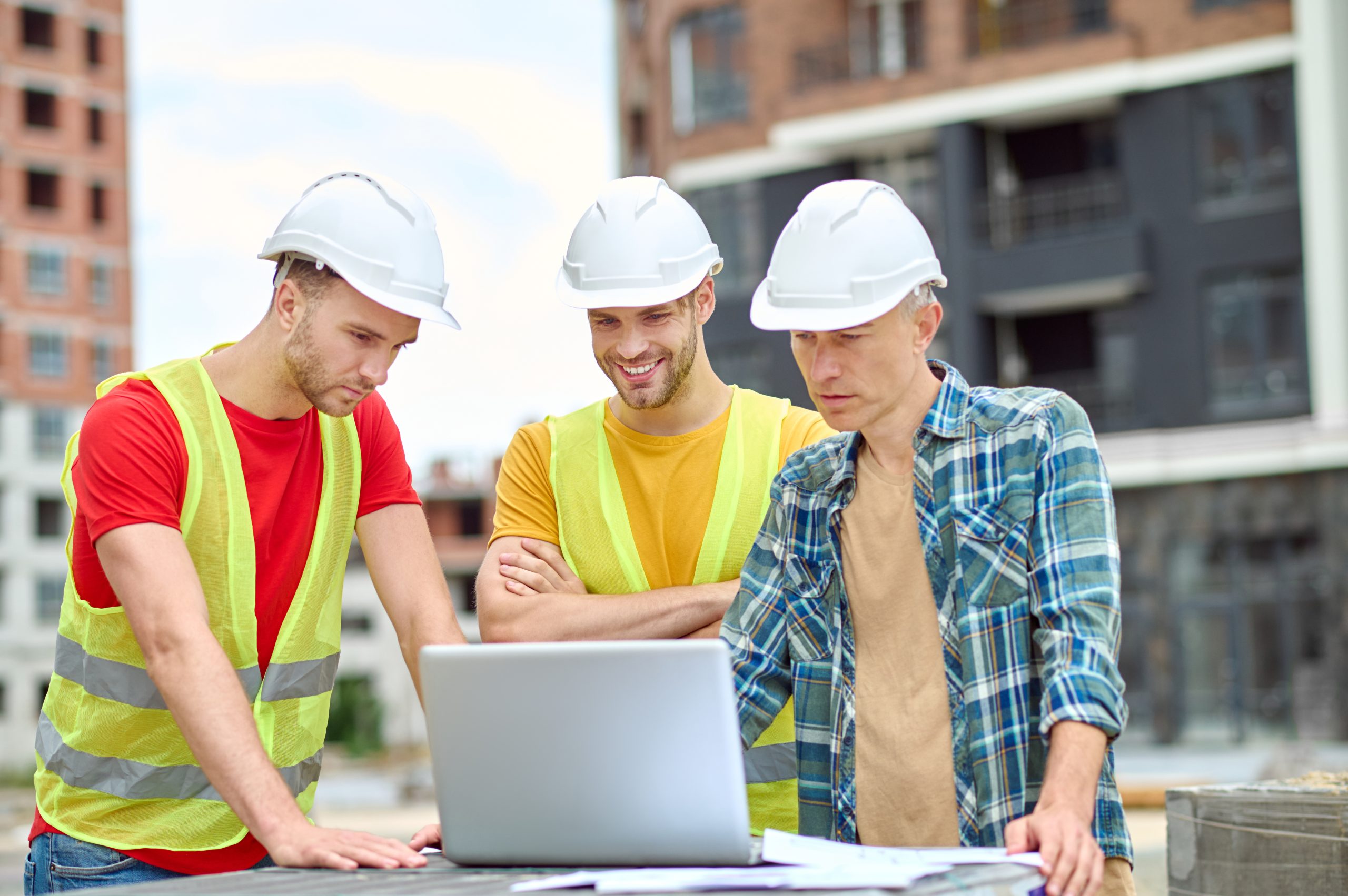 Project manager and engineers reviewing data on a laptop on a construction site