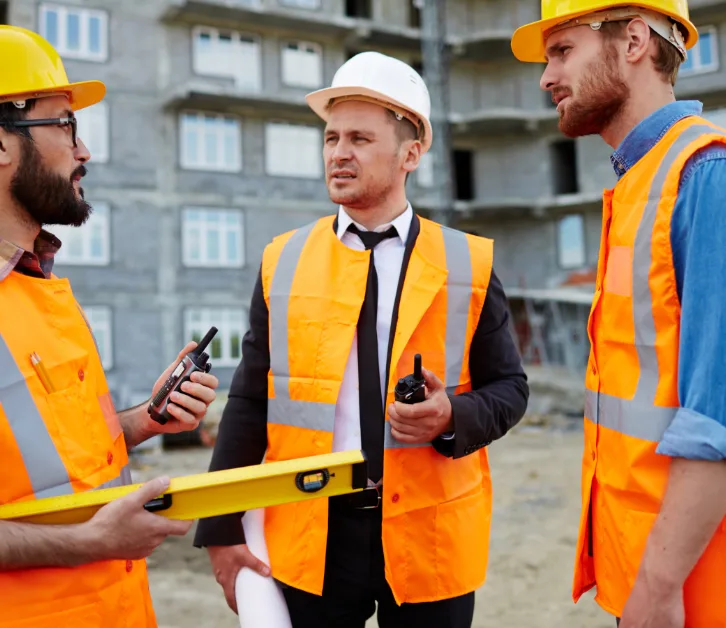 Quality inspectors in hard hats discussing a works handover on site